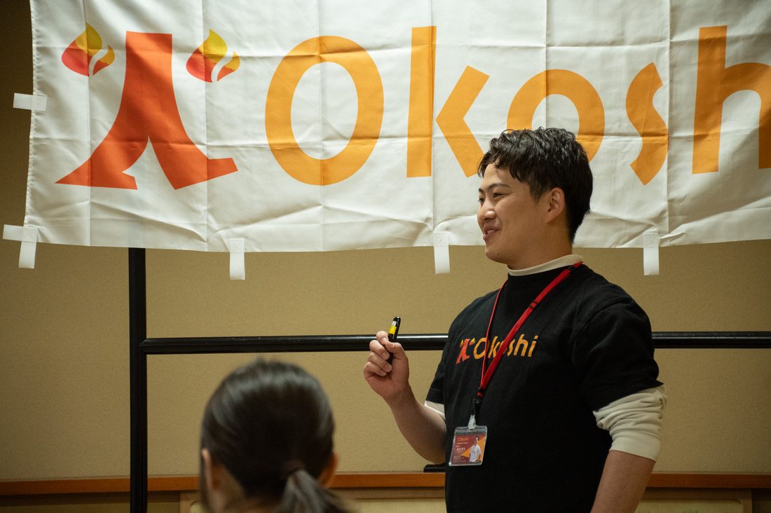 火-Okoshiのバナーの前で話す登壇者